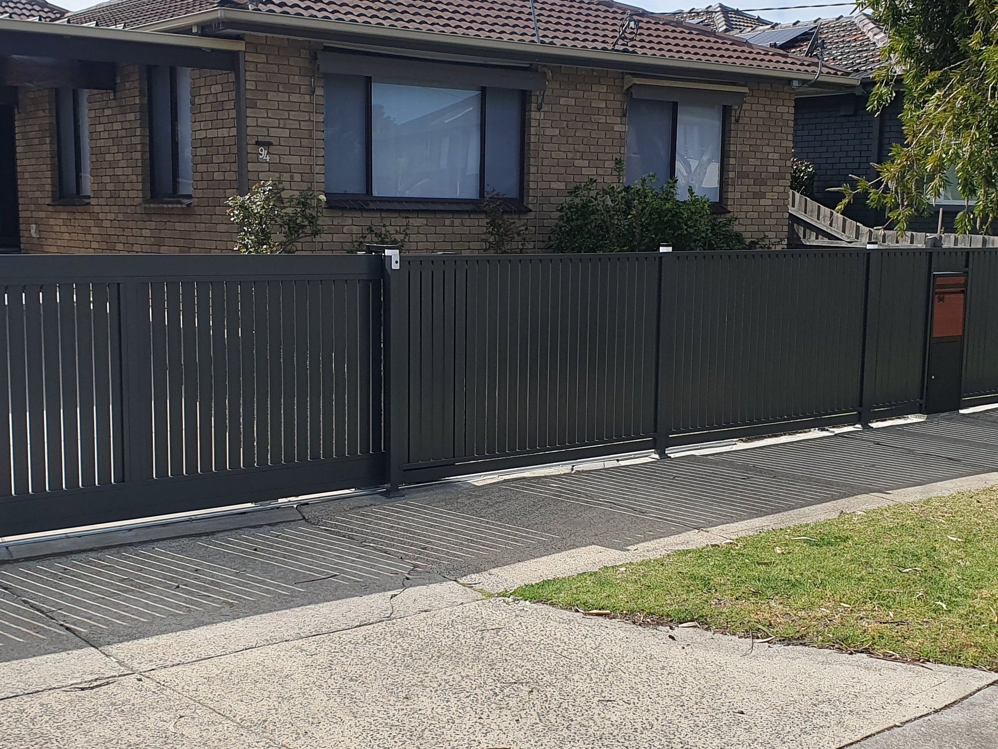 House with a driveway and sliding gate and black slat aluminium metal gate and fence
